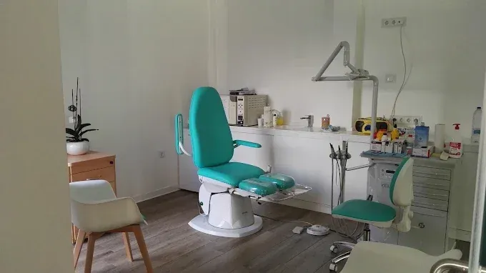 Sillón podológico turquesa de la Clínica Nuria Infantes con lámpara de tratamiento y productos sobre la encimera.
