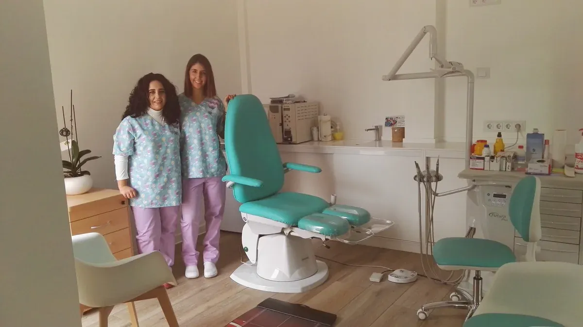 El equipo de la Clínica Podológica Nuria Infantes: dos podólogas junto al sillón de tratamiento, en la consulta de Daimiel.